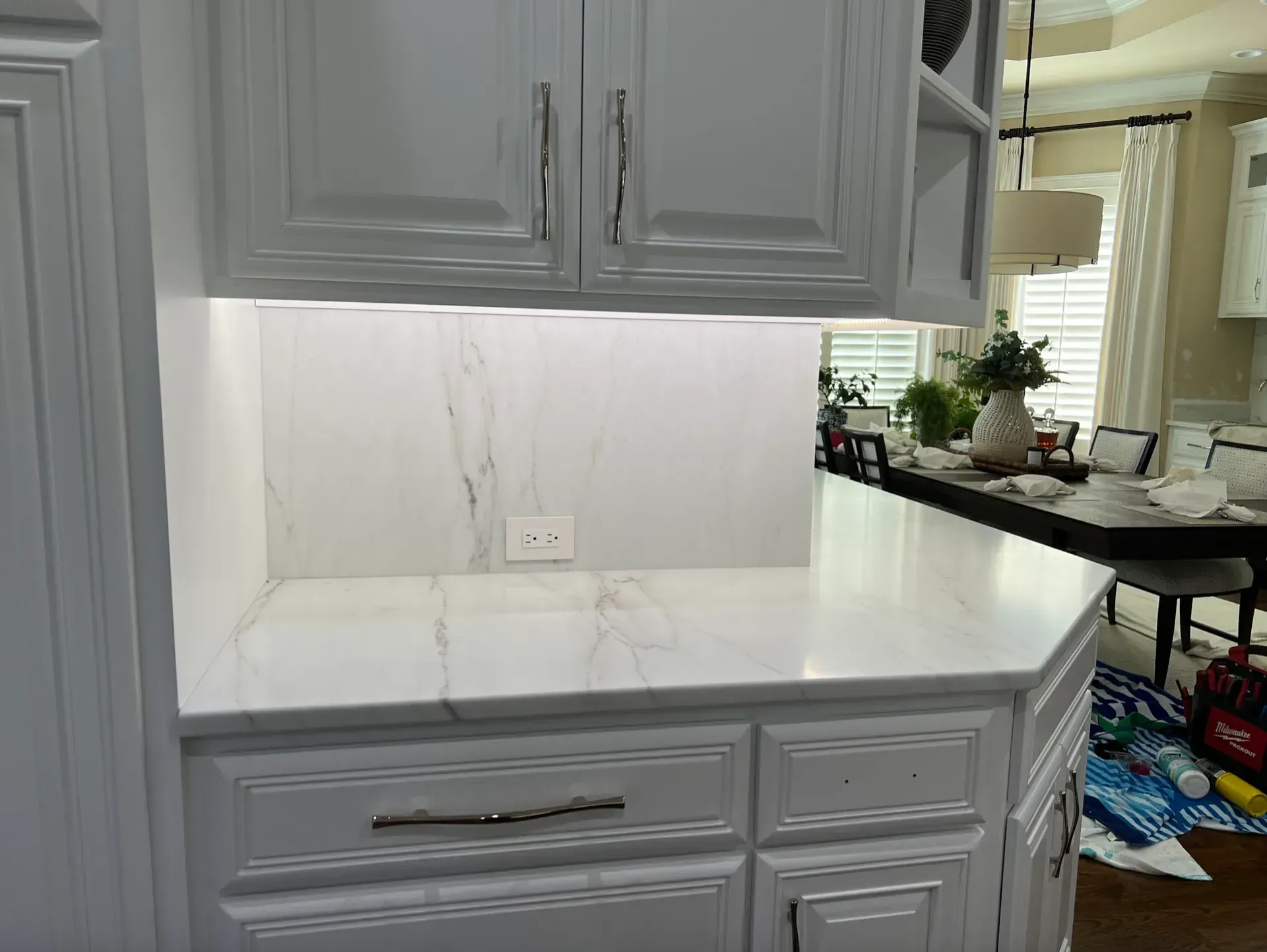 White kitchen cabinets with marble countertops and backsplash.